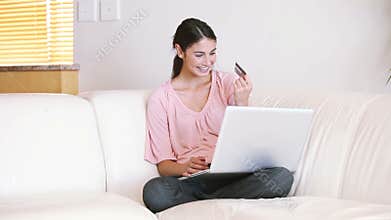 Lady sitting on the couch while using her credit card