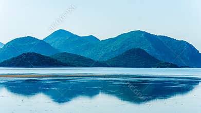 Calm sea with distant mountains and reflection in water