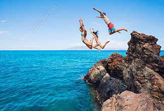 Friends cliff jumping into the ocean