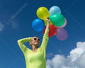 Woman holding balloons against cloud