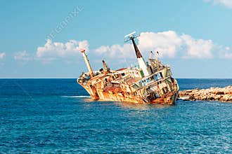 The Edro III, Pegeia, Cyprus - weathered shipwreck off the coast: rusted vessel leaning on breakwater in bright blue sea