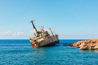 Rusty the Edro III shipwreck adrift near rocky coast under clear blue sky at sea horizon calm day