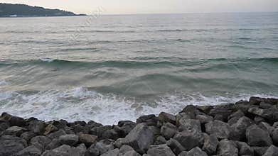 Waves breaking over rocks on the beach.