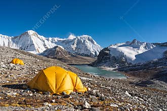 Yellow tents at Amphulapcha base camp surrounded by Himalaya mountains range in Everest region, Nepal