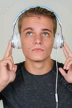 Face of young blond handsome man thinking while listening to music