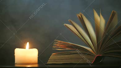 Near the open book, a candle burns and colored, magical smoke flies.