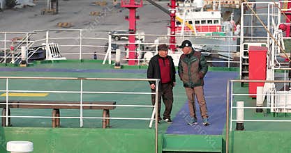 Asians stroll along the open deck of a passenger ferry.