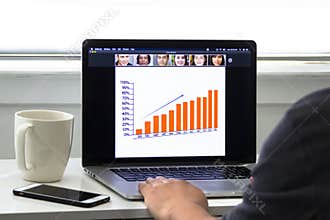 An office worker working from home having a Zoom meeting call looking at a presentation on a