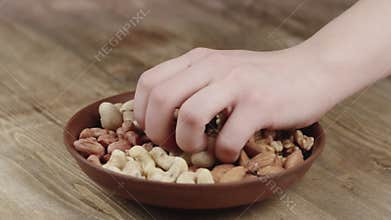 Woman Picks Up a handful of nuts, To Eat, From Her Bowl. took a nut on the left side