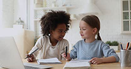 Happy afro american and caucasian kid girls playing studying together