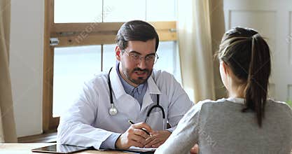Young male general practitioner consulting female patient at checkup.