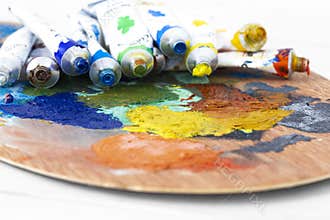 Artists oil paint tubes open and used on a wooden palette,  with mixed colours.  Art and craft supplies