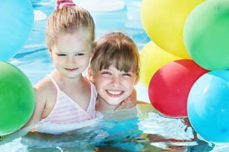 Children playing with balloons in swimming pool.