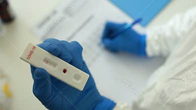 Doctor in a protective suit and gloves holds in his hand a used test cartridge rapid test covid-19. Registration of a