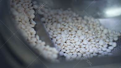 White pills is moving on automatic line during working day in pharmaceutical factory spbd.