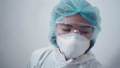 Asian female nurse wearing white ppe suit, medical protective suit, protective glasses, n95 mask and face shield pandemic covid-19