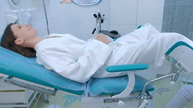 Young patient woman in a gynecological chair in clinic, side view.
