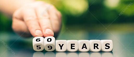 Hand turns dice and changes the expression `59 years` to `60 years`.