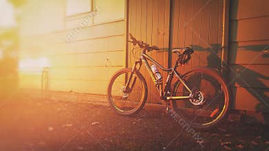 Mountain bike against doorway in sunset evening
