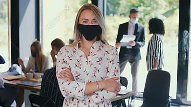 COVID-19 as new normal. Portrait of young happy gen-z 20s blonde business woman in face mask at light office slow motion