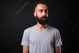 Young handsome Persian man with dreadlocks against black background