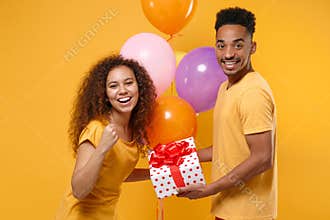 Joyful friends couple african american guy girl isolated on yellow background. Birthday holiday party concept. Celebrate