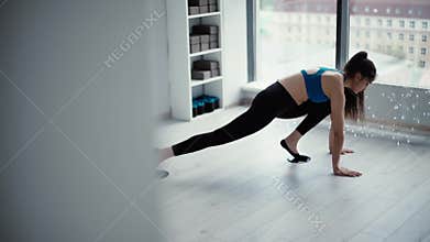 Woman fitness trainer stretching their legs on gym floor using gliding disk