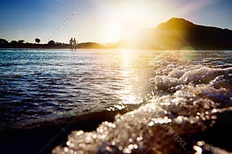 Stunning sunset on the beach of Noja with infinite horizon and solitary figures in the distance. Foamy waves and hills in the back