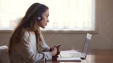 Serious girl student wear headphone study online with internet teacher