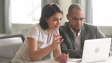 African and asian colleagues talking looking at laptop in office