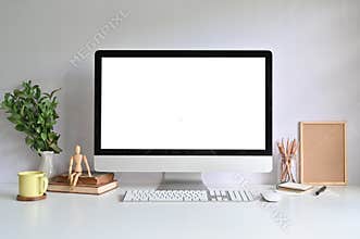 PC computer on workspace with coffee mug, pencil, books and plant on office desk