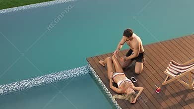 Sexy man applying suntan lotion on female body. Happy couple enjoying sunbathing