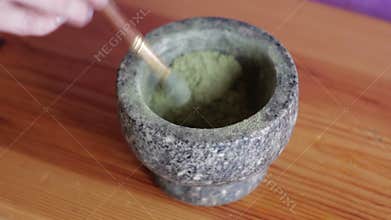 Hand pounding pine needles at spices in stone mortar