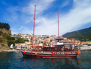 Parga city, greek summer tourist resort with colorful houses and sailing boat with tourists