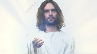 Holy man in white robe reaching out hand blessing and healing needy, religion