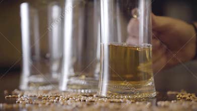 Male hand puts a half-empty beer glass on the table close-up. Peanuts are scattered on the table. Advertising concept.