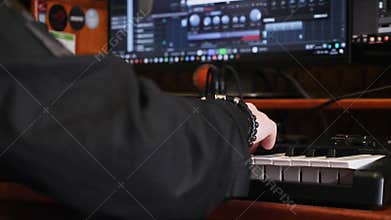 Young artist composing a song on electronic piano keyboard at home recording studio. Hand playing on piano in music studio. Sound
