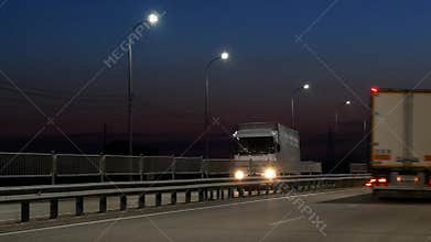 Semi trucks on the highway carrying freight container. Lanterns at night along the road