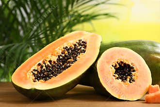 Fresh juicy cut papayas on wooden table against blurred background