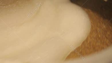 Beer is brewed and fermented in large aluminum tanks. Foam on the surface. Close-up.