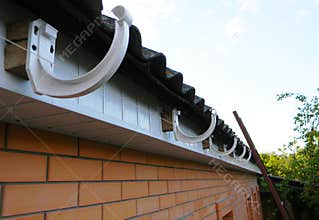 Roof gutter holders installation. House rain gutter holders installing