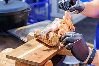 Chef serves wooden desk with seafood and sweet grilled corn at the festival. Street food prepared on grill