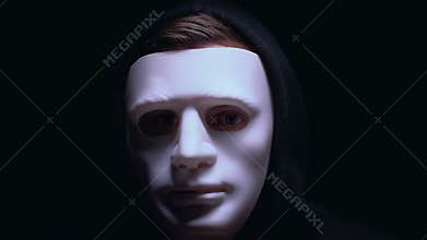 Man hiding wounded face under mask, isolated on black background, criminal