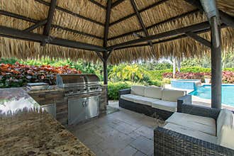 Outdoor tiki hut with outdoor grill kitchen and pool