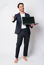Full body shot of happy Hispanic businessman showing laptop and giving thumbs up
