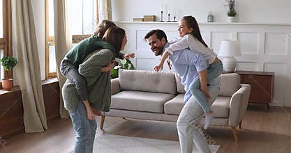 Funny happy parents carrying kids playing game in living room