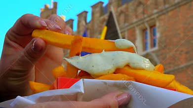 Hand takes french fries diped in delicious sauce