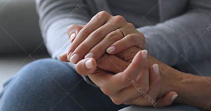 Young woman holding old female hands giving support, close up