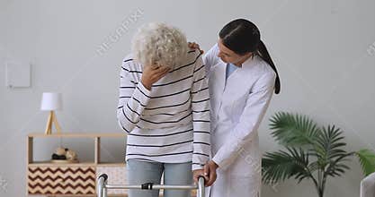 Young woman caregiver supporting consoling sad disabled old grandma patient
