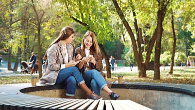 Happy girls browsing social media using smartphones in public park